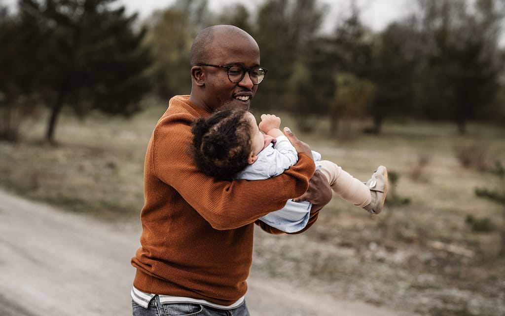 Papa mit kleinem Kind im Arm drehen sich im Kreis und lachen