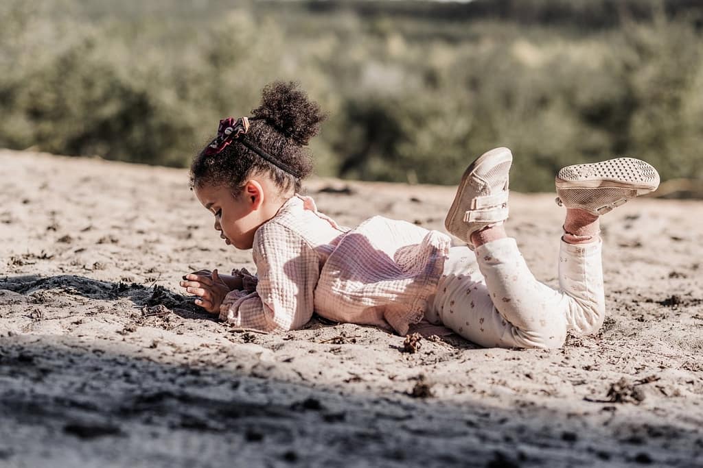 Kleines Kind liegt im Sand auf dem fränkischen Dünenweg