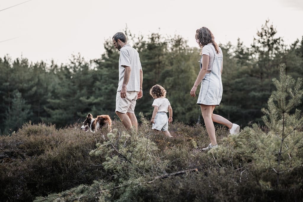Familie mit Hund läuft hintereinander durch die Heide am Fränkischen Dünenweg.