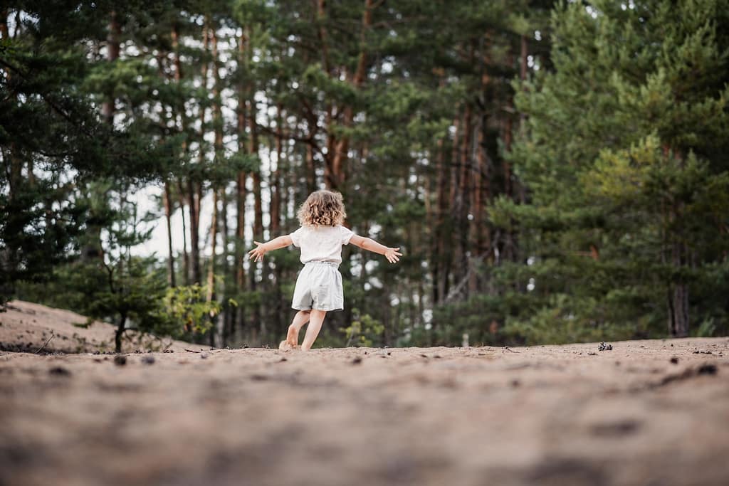KLeines Kind rennt mit ausgebreiteten Armen in der Natur am Fränkischen Dünenweg.