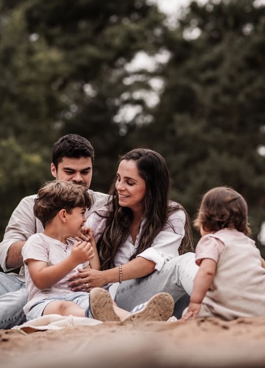 Familie mit 2 Kindern, junge und mädchen, auf einer Sanddüne in Nürnberg beim Familienfotoshooting. Sie lachen miteinander.