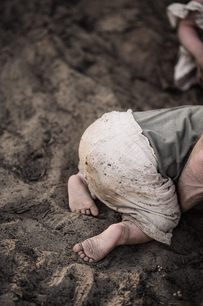 Baby sitzt von hinten im warmen Sand und spielt.