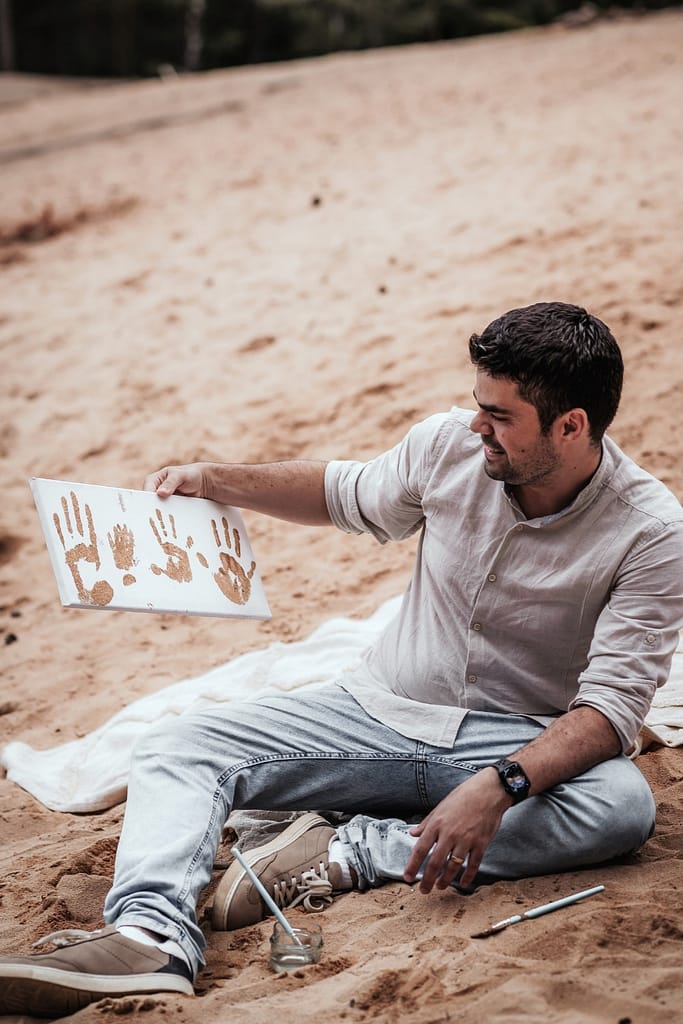 Papa mit einem einer Leinwand mit den Sand-Fingerabdrücken der Familie