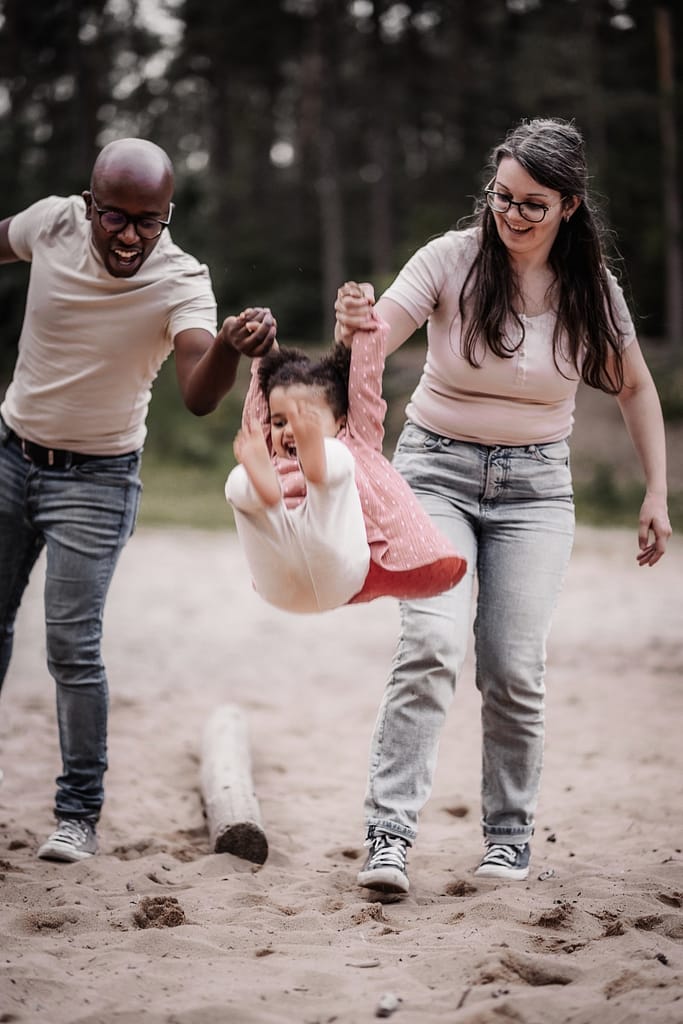 Mama, Papa und Kind auf der Sanddüne spielen Engelchen Flieg