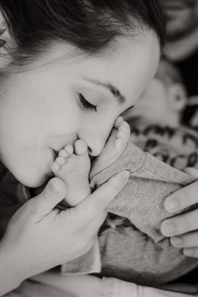 Mama küsst Babyfüße ihres Neugeborenen. Schwarz-Weiß-Foto beim Newbon-Shooting Nürnberg