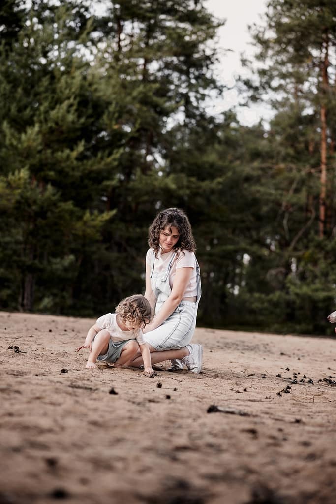 Mama hockt mit ihrer kleinen Tochter im Sand am fränkischen Dünenweg.
