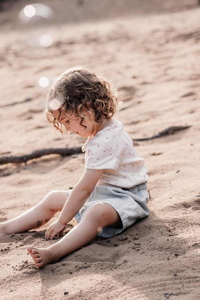 KLeines Kind sitzt im Sadn und spielt am Dünenweg bei Nürnberg beim Familienshooting.