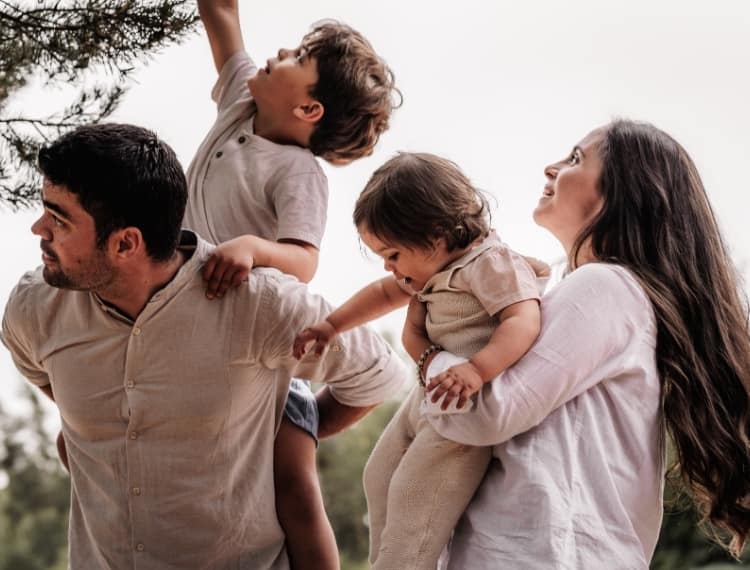 Familie mit 2 kleinen Kindern beim Pflücken von Zapfen einer Kiefer in Nürnberg bei einem Familienfotoshooting.