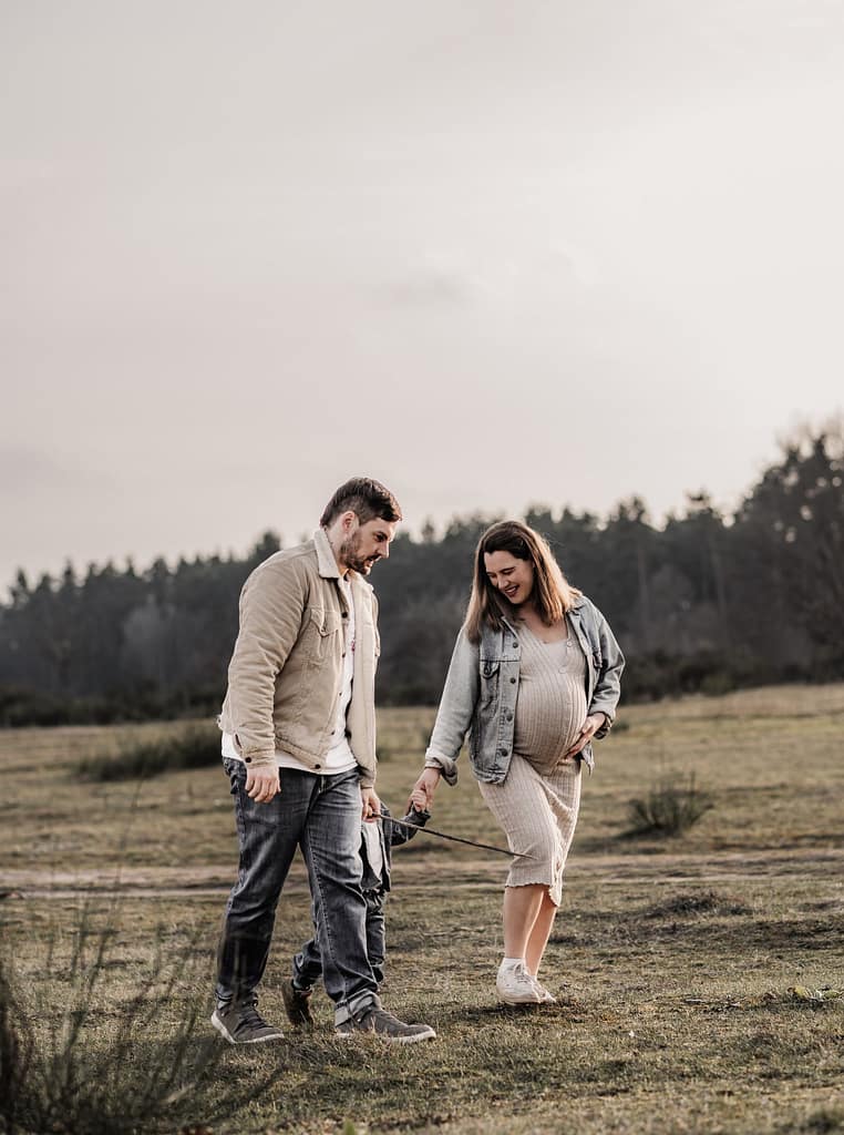 Familien draußen in der Natur beim Familien und Babybauchshooting. Sie genießen die gemeinsame Zeit auf einer Wiese umgeben von Wald.